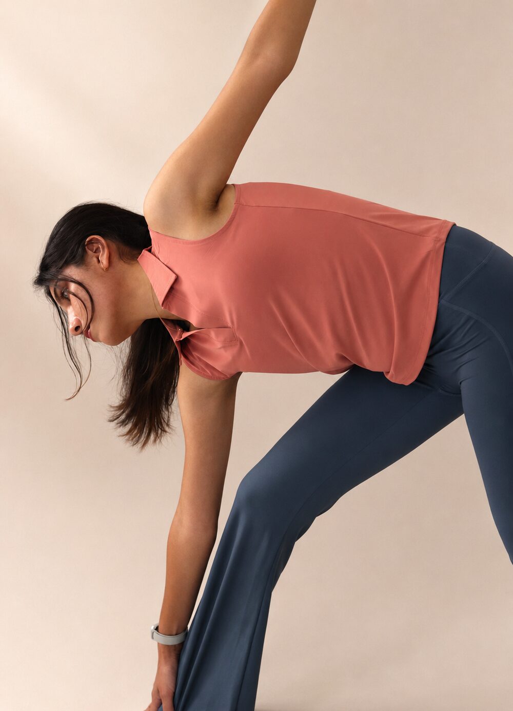 Model stretching in a Rosewood Golf Tank and Moonlight Flared Leggings